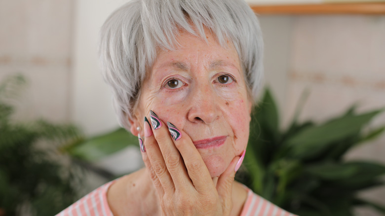 An older woman shows off her colorful stiletto nails.