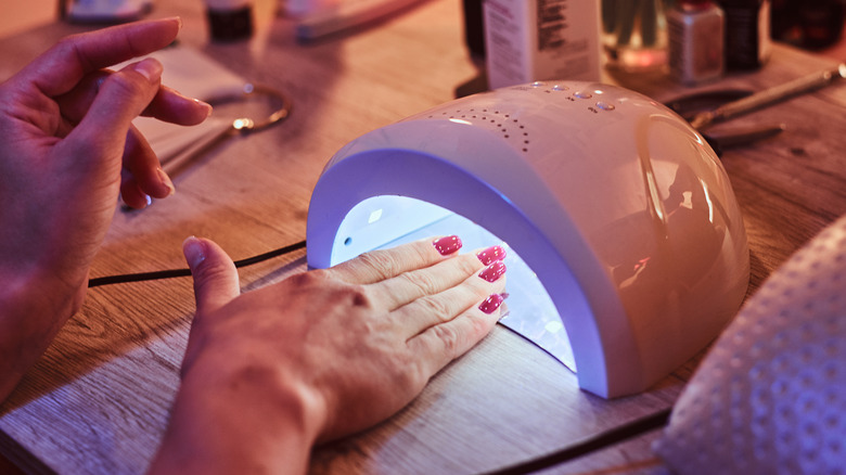 Woman curing red gel nails