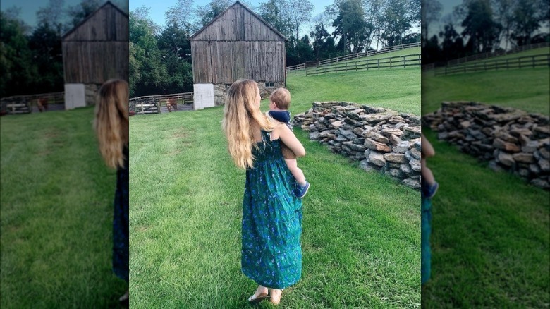 Woman holding toddler on farm