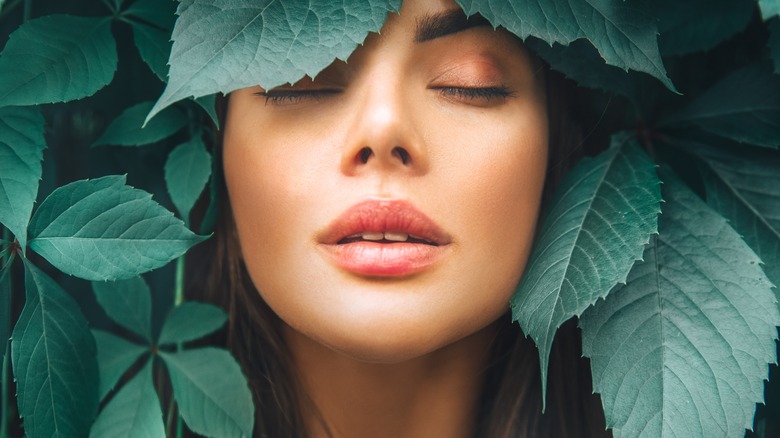 woman surrounded by green leaves