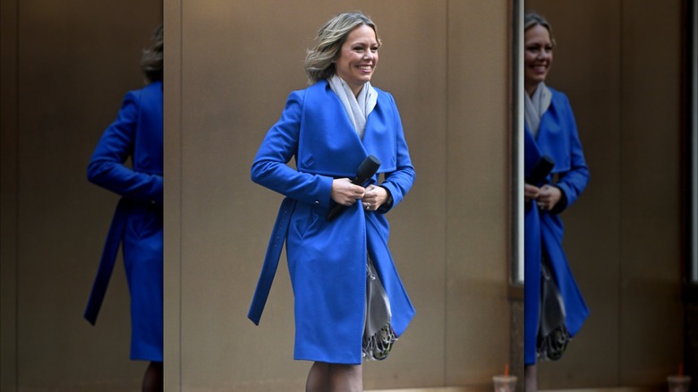 Dylan Dreyer buttons up her blue coat as she walks outside with a microphone