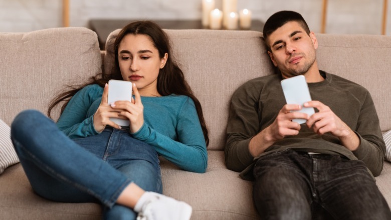 Couple texting on the couch