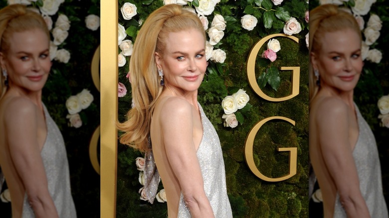 Nicole Kidman posing in a silver dress with a dramatic hairpiece at the 2025 Golden Globes