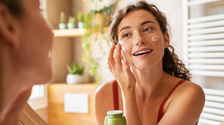 woman applying skincare in bathroom