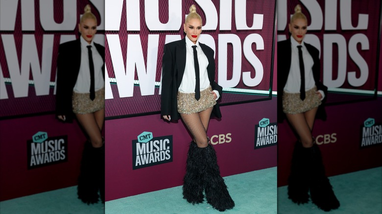 Gwen Stefani arriving at the 2023 CMT Awards in gold micro-shorts and a black-tie outfit on top