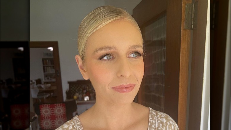 Woman wears slicked back bun with side part