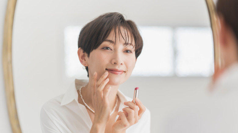 Woman applying pink lipstick
