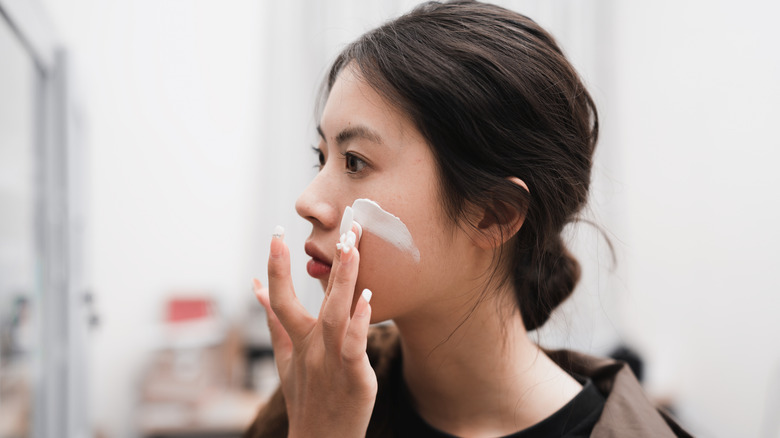 Woman applying cream to her face