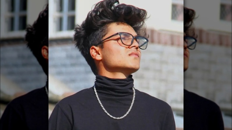 Man wears black turtleneck with subtle shoulder pads 