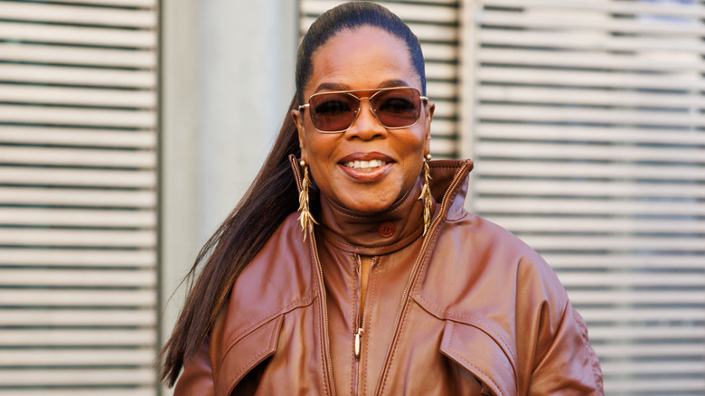 Oprah Winfrey in a leather jumpsuit and sunglasses smiling