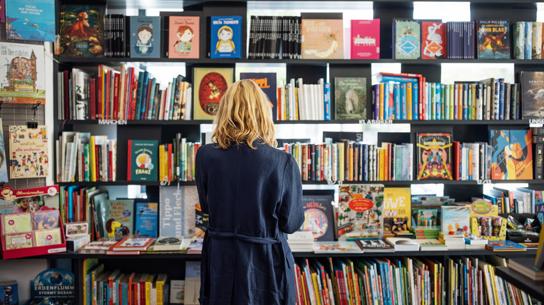 A woman browsing through a bookshop with a large selection of books