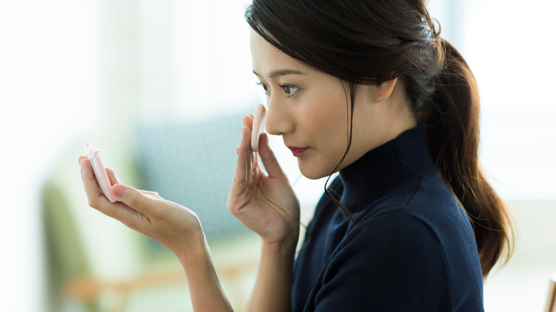Woman using compact mirror to fix makeup