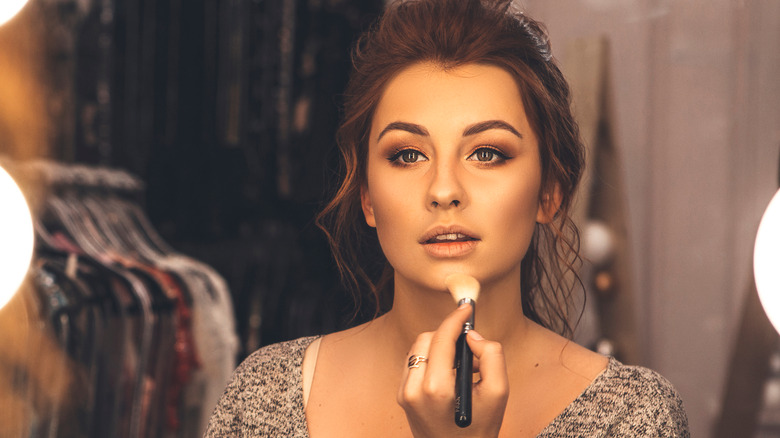 Woman applying makeup to her chin