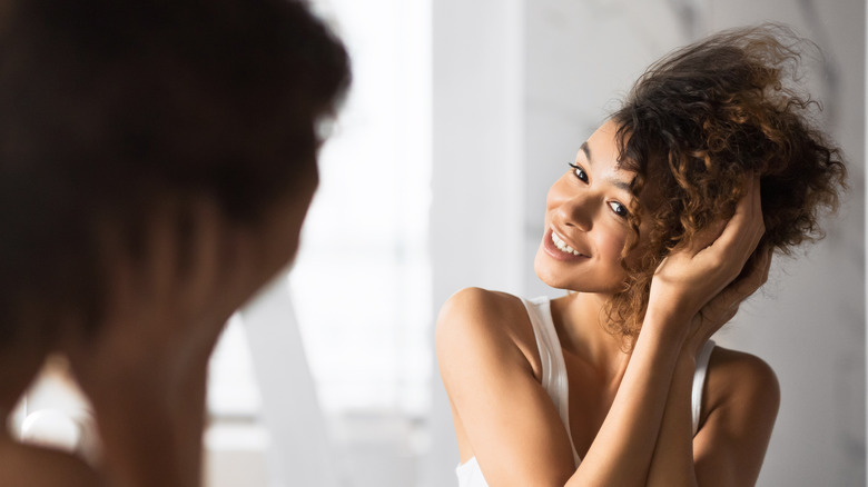 Girl touching thick hair in mirror