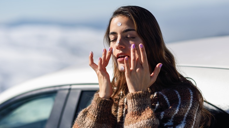 Woman putting sunscreen on face
