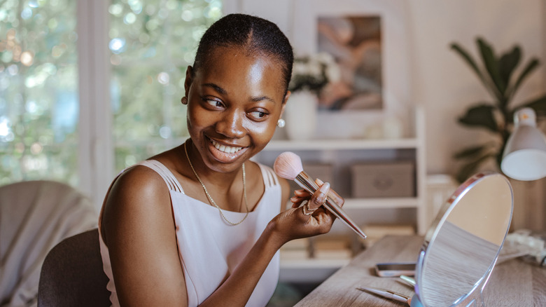 Woman holding a fluffy brush and applying makeup