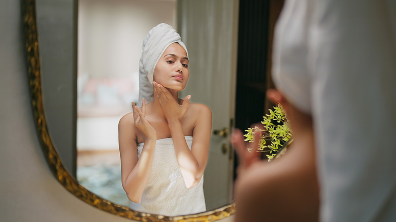 Woman in a towel looking in the mirror