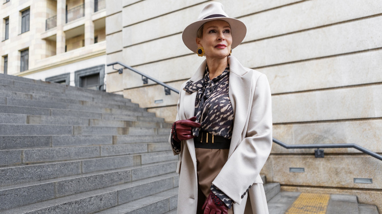 A woman wearing a white fedora, marron gloves, and a statement belt