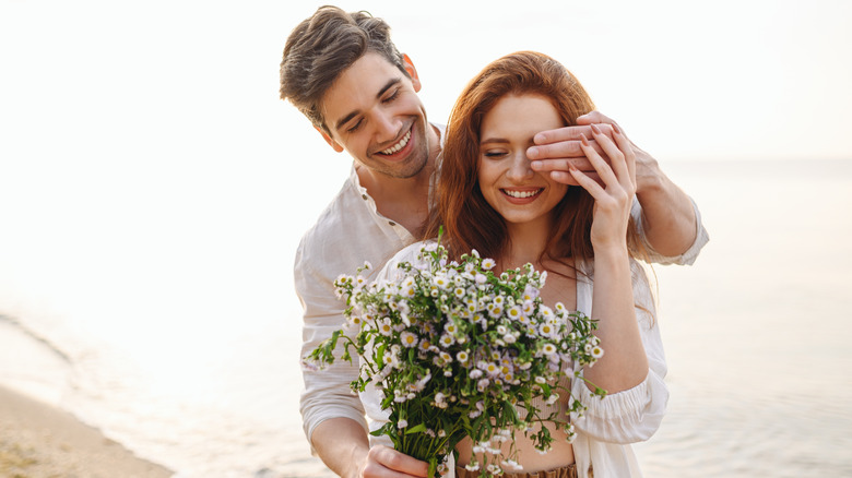 Man surprising woman with flowers