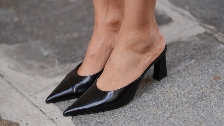 Person wearing patent leather pointy mules