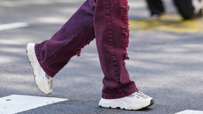 A woman wearing chunky sneakers with maroon pants