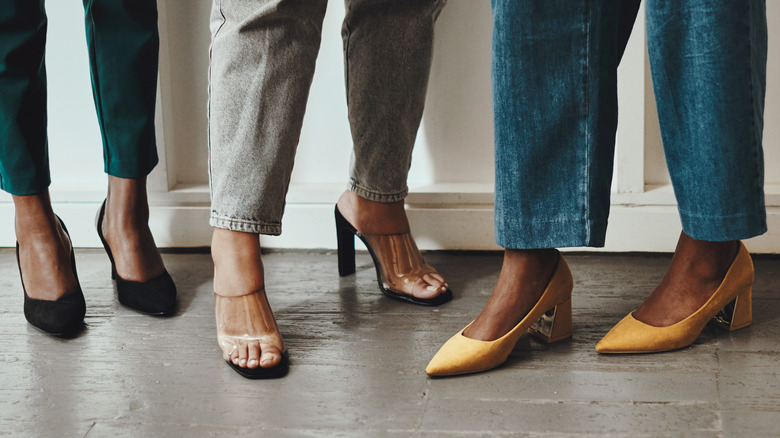 Women standing together in a room wearing different types of shoes