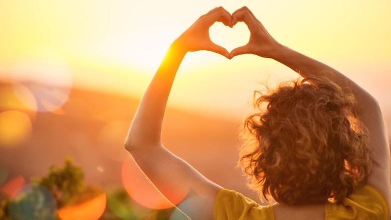 A woman holds up her hands in a heart shape
