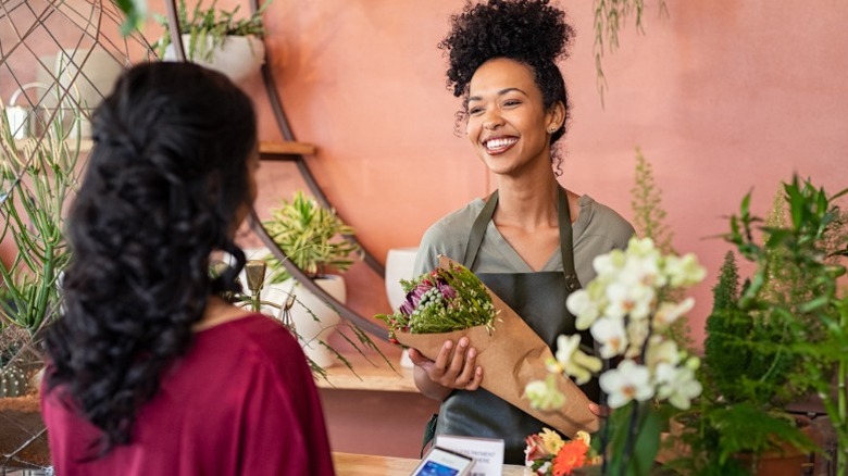 A woman buys flowers from a smiling florist