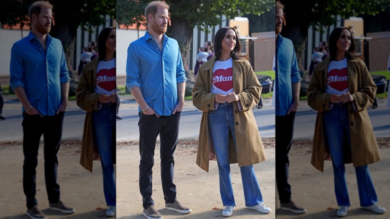 Meghan Markle pictured with Prince Harry wearing a graphic tee, jeans, and a trench coat