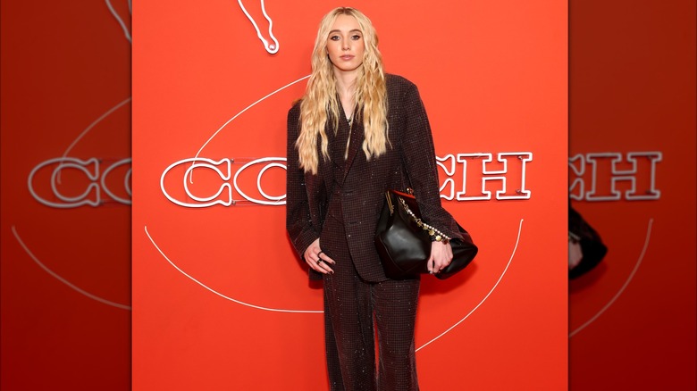 Paige Bueckers posing for a picture at the 2025 WNBA Draft wearing a black pant suit and the big orange bag that landed her on teh Worst Dressed list