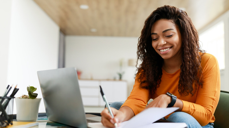 Woman working on laptop, writing