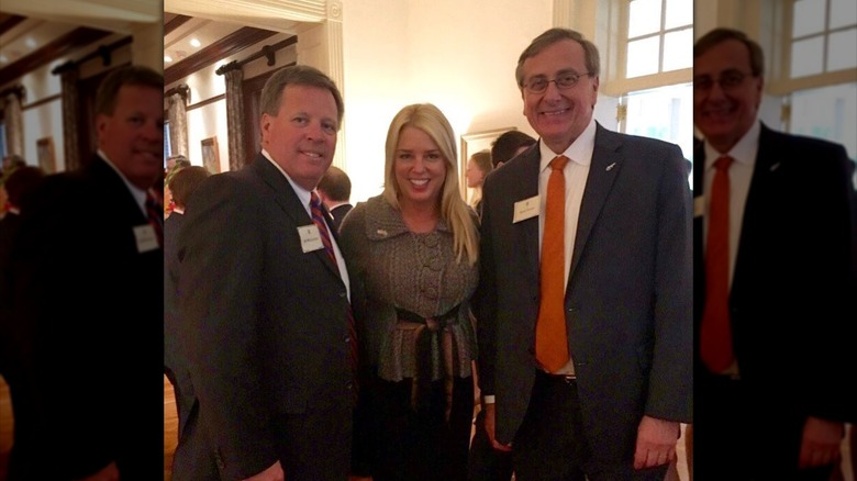 Pam Bondi is flanked by the president and coach from University of Florida