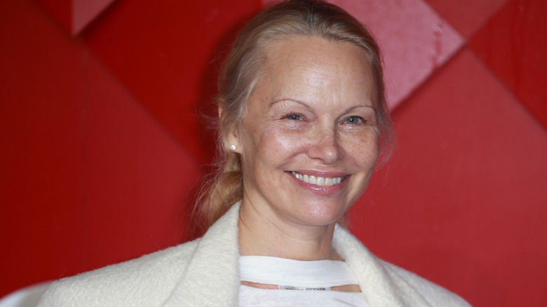 Pamela Anderson wearing a white outfit and smiling without makeup