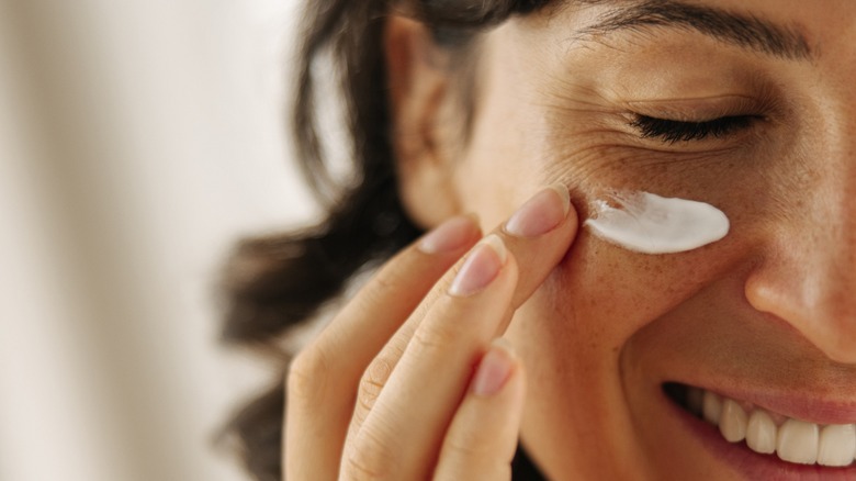 woman applying cream to face