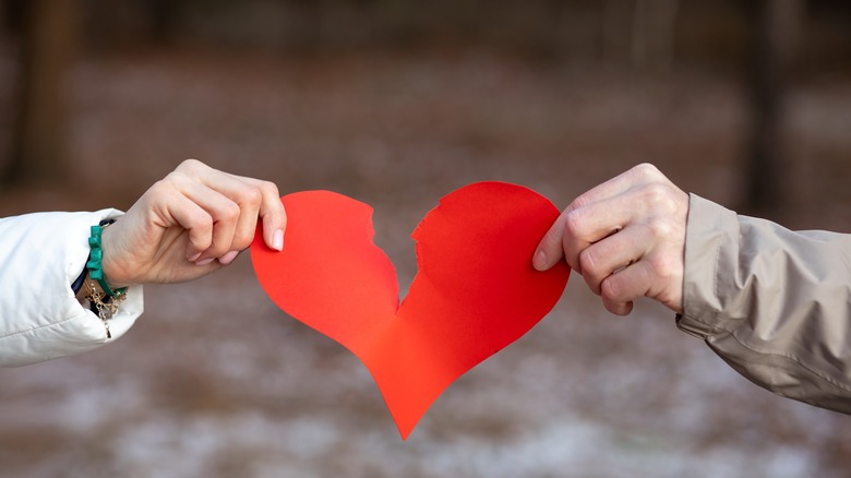 hands tearing paper heart appart