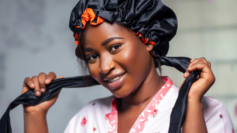 Woman putting on hair bonnet for bed