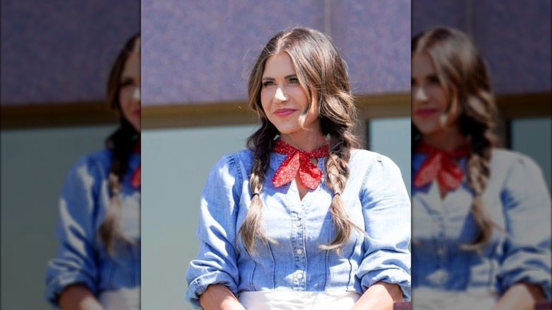 Kristi Noem stands outside a building in Southern garb