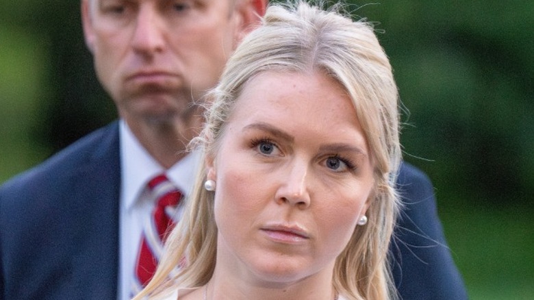 Karoline Leavitt listens as Donald Trump speaks to the press