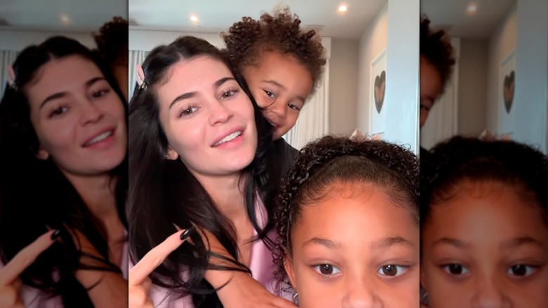 Kylie Jenner with light makeup posing with her two children Stormi and Aire Webster