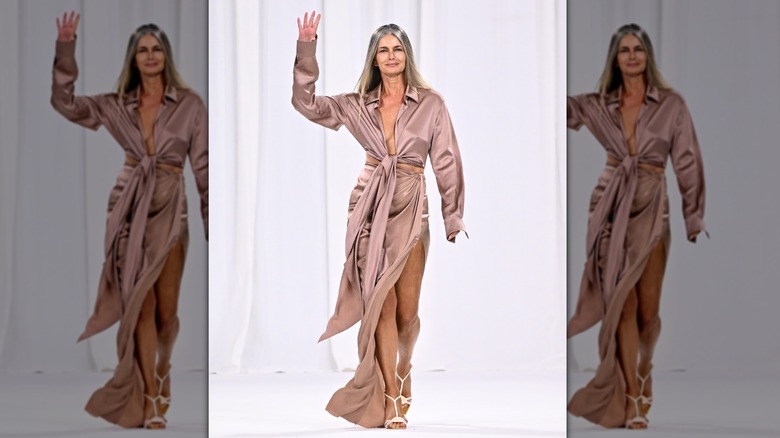 Paulina Porizkova walking the runway in a beige silky dress at a Balmain fashion show.