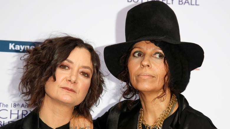 Sara Gilbert poses for the camera while Linda Perry rests her arm on her shoulder on a red carpet