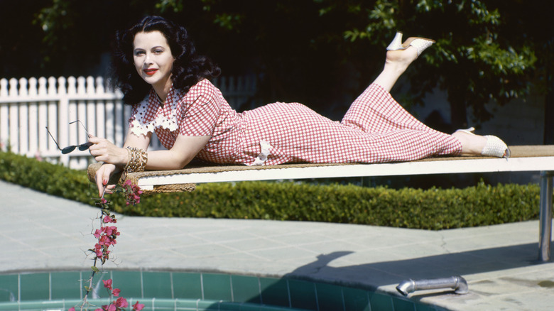 Hedy Lamarr lounges on a diving board wearing a gingham dress