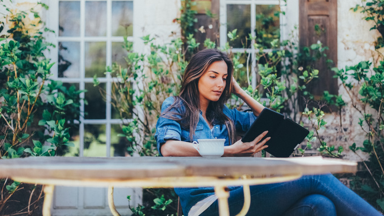 Woman sitting, reading outside