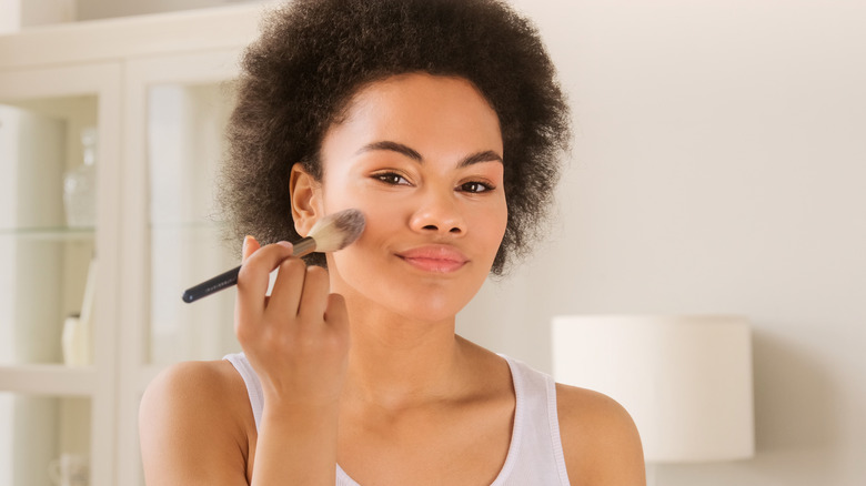 smiling woman applying powder blush