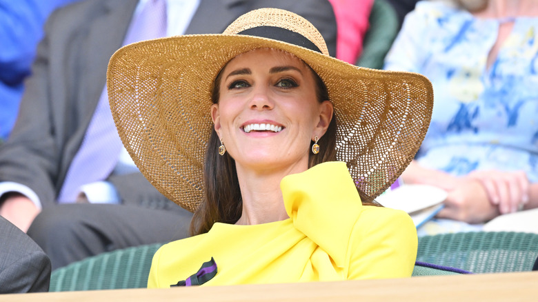 Kate Middleton wearing a straw hat with a yellow outfit at Wimbledon in 2022