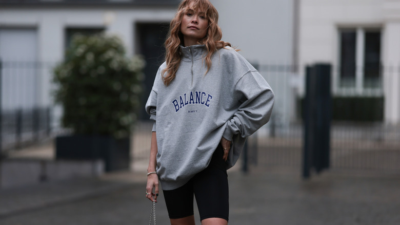 Woman poses in biker shorts and sweatshirt
