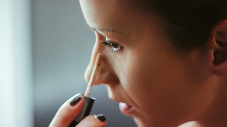 woman applying concealer under eyes