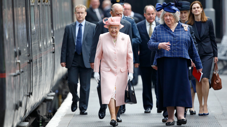 Queen Elizabeth standing out in pale pink amongst a crowd of people