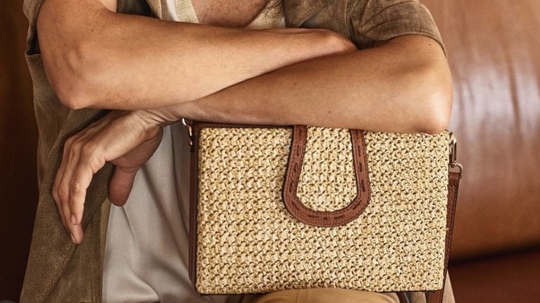 resting forearms on raffia clutch