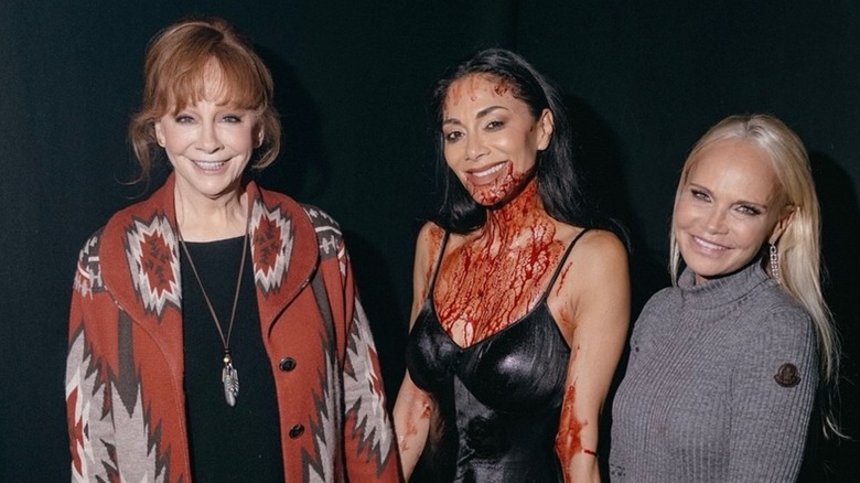 Reba with messy hair posing alongside Kristin Chenoweth and Nicole Scherzinger.